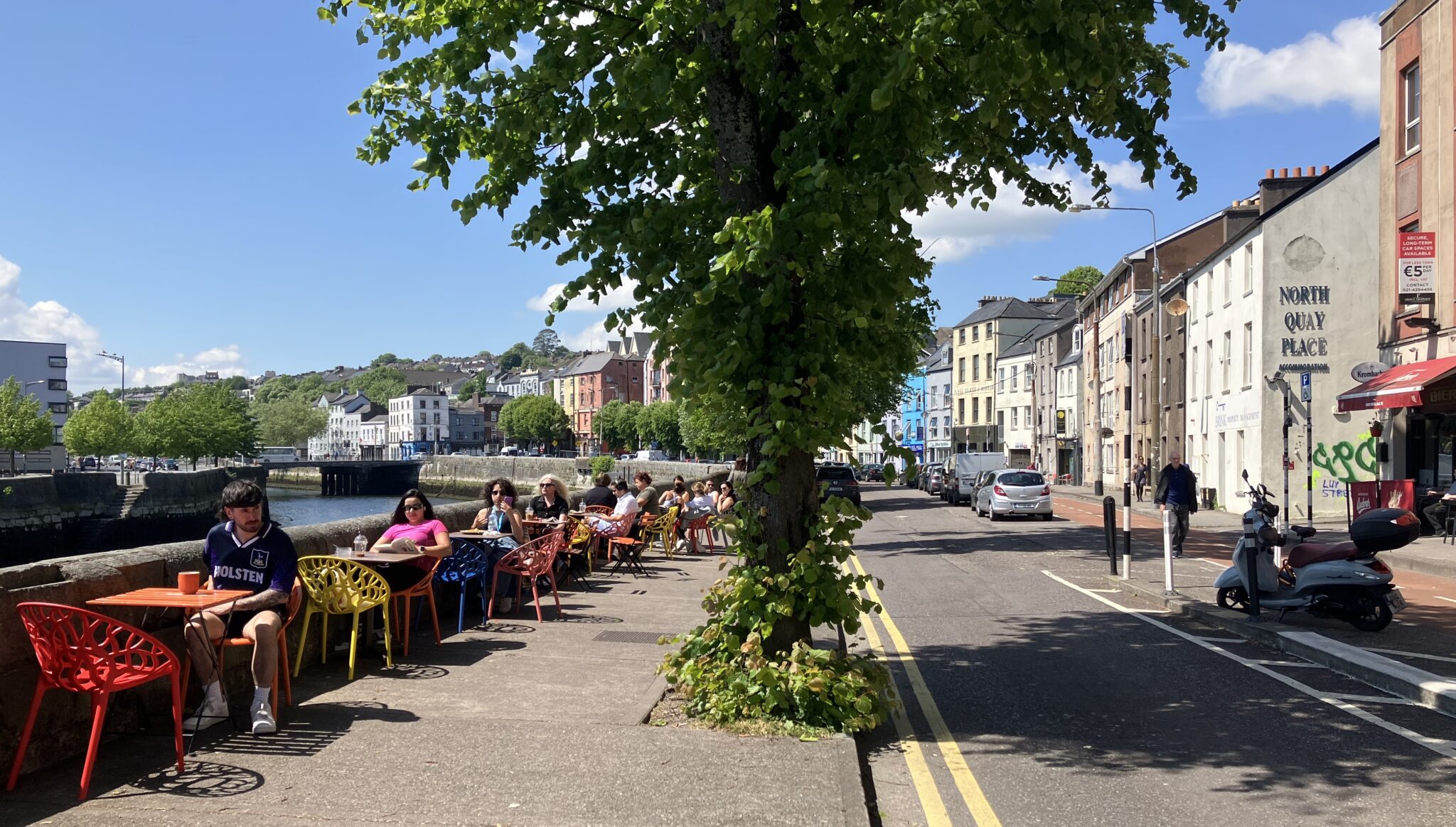 People sitting outside at a café, by the river in Cork